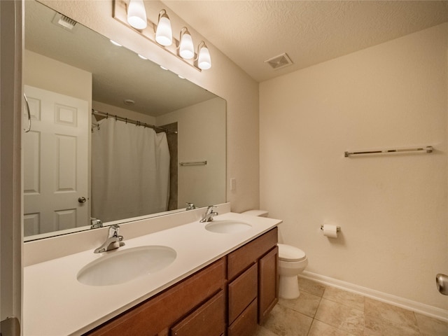 bathroom with tile patterned floors, vanity, toilet, and a textured ceiling