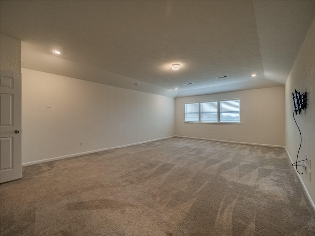 carpeted empty room with vaulted ceiling