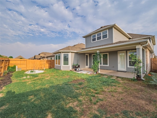 rear view of house featuring a lawn and a patio area