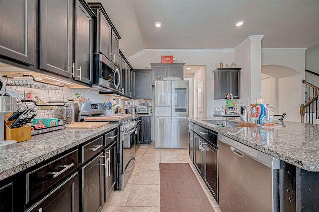 kitchen with decorative backsplash, appliances with stainless steel finishes, vaulted ceiling, sink, and light tile patterned floors