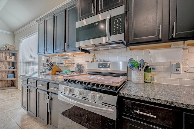 kitchen with appliances with stainless steel finishes, tasteful backsplash, vaulted ceiling, stone counters, and light tile patterned flooring