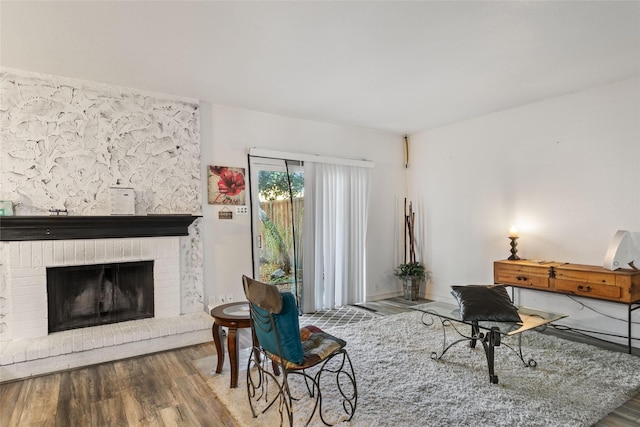 sitting room featuring wood-type flooring and a brick fireplace