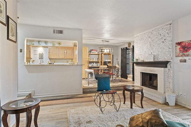 living room with a brick fireplace and light wood-type flooring