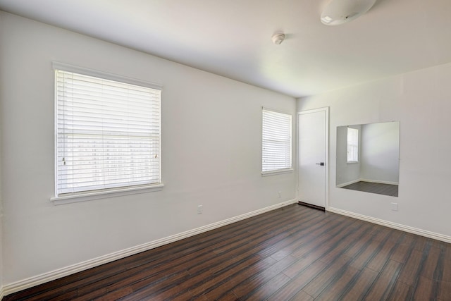 unfurnished room featuring plenty of natural light and dark wood-type flooring