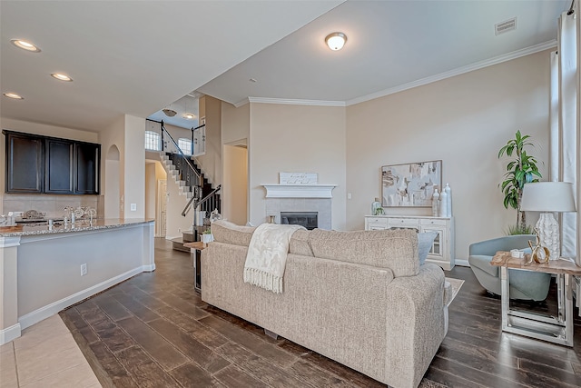 living room with a tile fireplace, dark hardwood / wood-style flooring, ornamental molding, and sink