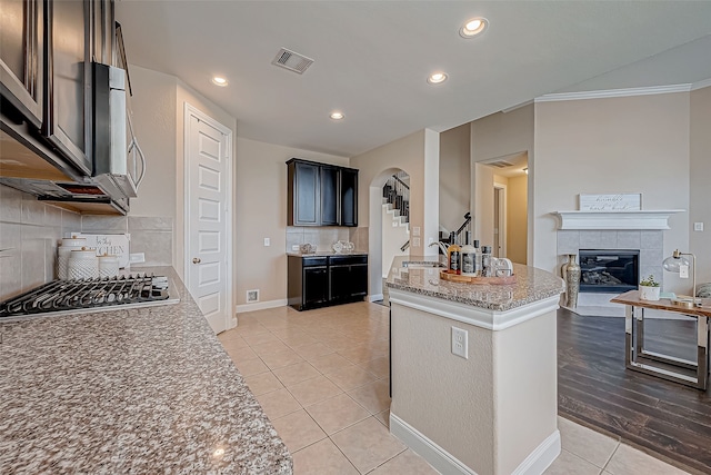 kitchen featuring a center island, ornamental molding, appliances with stainless steel finishes, light hardwood / wood-style floors, and light stone counters