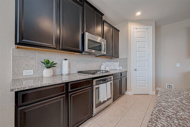 kitchen featuring backsplash, light stone counters, dark brown cabinets, stainless steel appliances, and light tile patterned floors