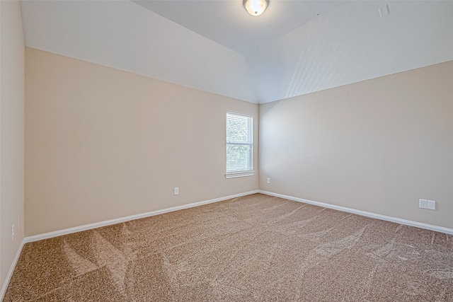 carpeted empty room with vaulted ceiling