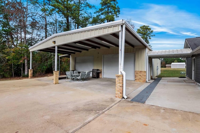 view of patio featuring a carport, a grill, a garage, and an outbuilding