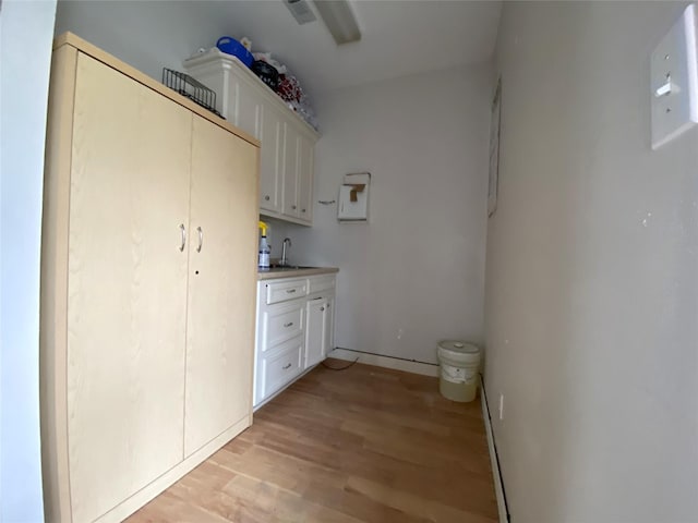 interior space featuring white cabinetry, light hardwood / wood-style flooring, and sink