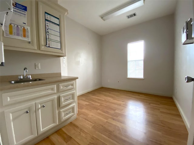 interior space featuring sink, light hardwood / wood-style floors, and cream cabinetry