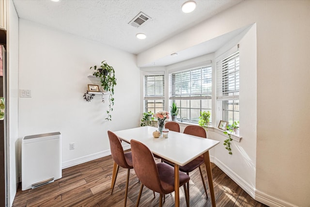 dining space with a textured ceiling and dark wood-type flooring