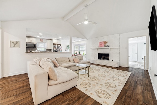 living room with vaulted ceiling with beams, dark hardwood / wood-style floors, a brick fireplace, and ceiling fan