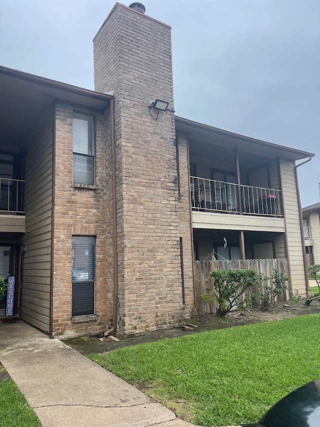 exterior space featuring a lawn and a balcony