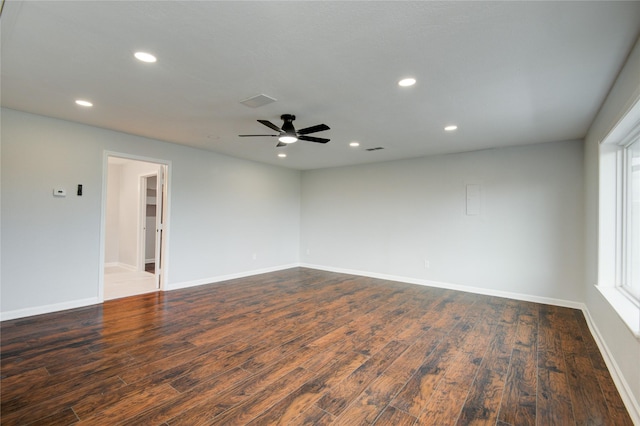 empty room featuring plenty of natural light, ceiling fan, and dark hardwood / wood-style flooring