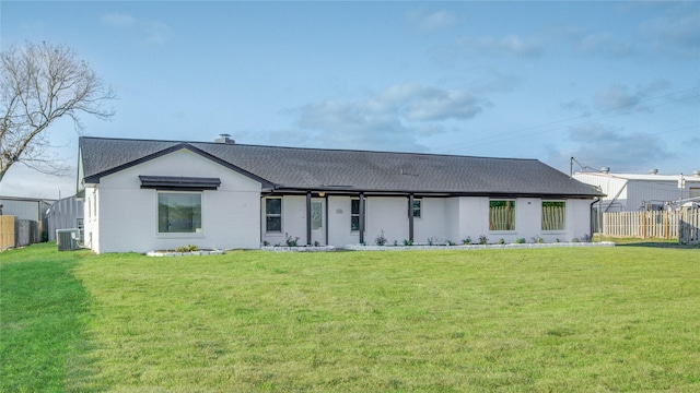 rear view of house featuring central AC and a lawn