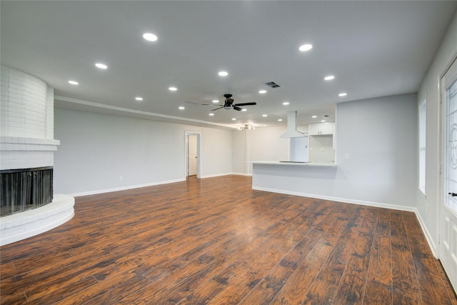 unfurnished living room with a fireplace, ceiling fan, and dark wood-type flooring