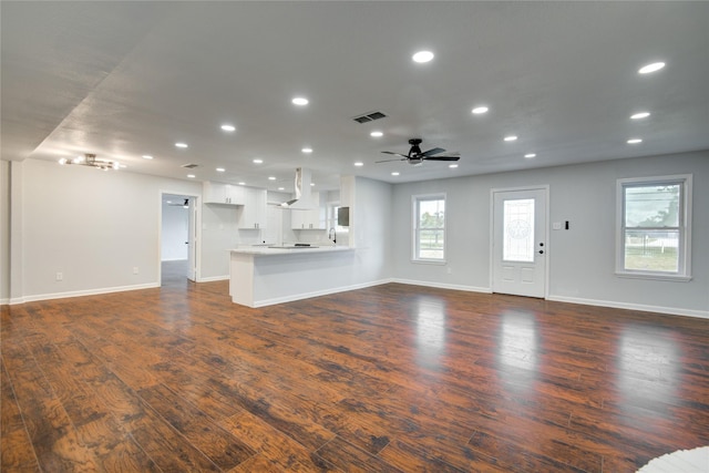 unfurnished living room with ceiling fan and dark wood-type flooring