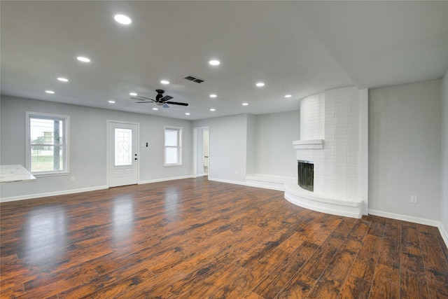 unfurnished living room with a fireplace, ceiling fan, and dark wood-type flooring