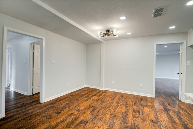 spare room with a textured ceiling and dark hardwood / wood-style floors