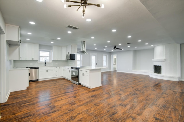 kitchen featuring appliances with stainless steel finishes, dark hardwood / wood-style floors, white cabinetry, and wall chimney range hood