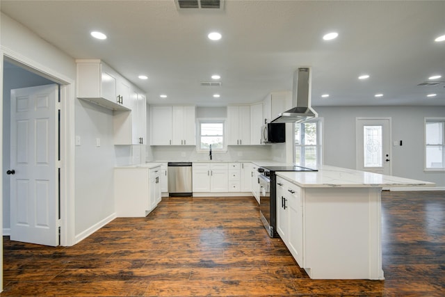 kitchen with exhaust hood, light stone counters, white cabinets, and stainless steel appliances