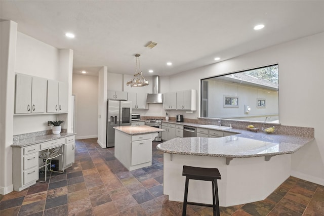 kitchen featuring a center island, kitchen peninsula, decorative light fixtures, a kitchen bar, and appliances with stainless steel finishes