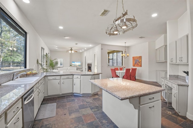 kitchen featuring a center island, stainless steel dishwasher, ceiling fan with notable chandelier, and sink