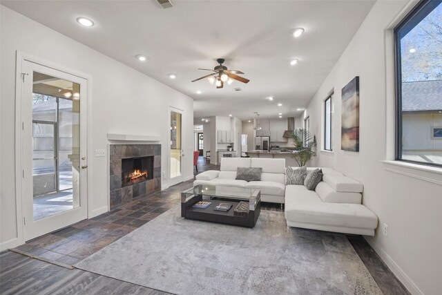 living room with a fireplace, dark hardwood / wood-style floors, and ceiling fan