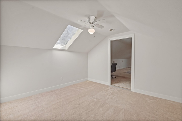 additional living space with light carpet, ceiling fan, and vaulted ceiling with skylight