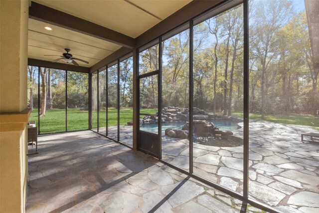 unfurnished sunroom featuring ceiling fan and beamed ceiling