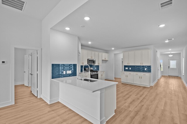 31915 Splendor Dr, Fulshear, TX 77441 - kitchen featuring stainless steel appliances, light wood-type flooring, white cabinetry, a sink, and backsplash