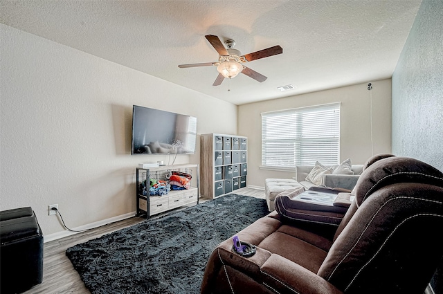 living room with ceiling fan, a textured ceiling, and light hardwood / wood-style flooring