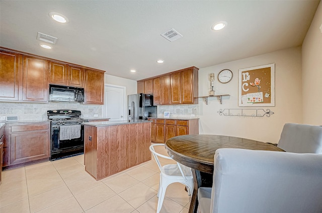 kitchen featuring light tile patterned floors, tasteful backsplash, a kitchen island, and black appliances