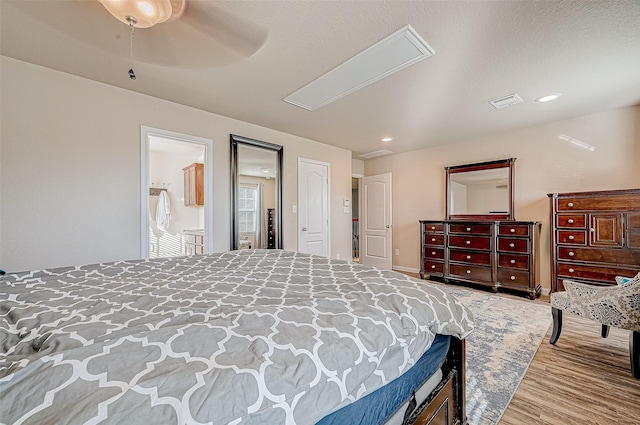 bedroom with connected bathroom, light hardwood / wood-style floors, and ceiling fan