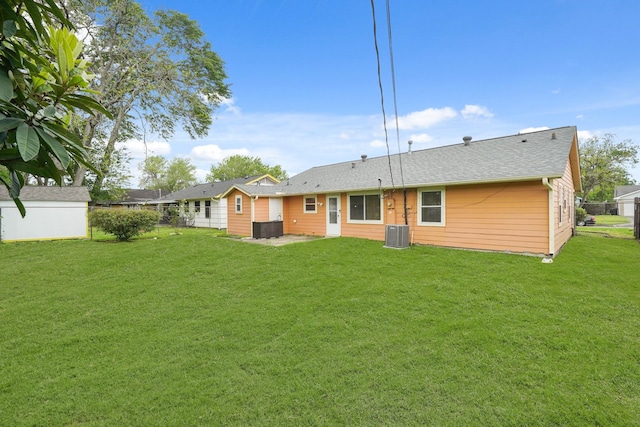 back of property featuring a lawn, central AC unit, roof with shingles, and fence