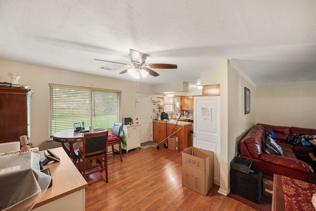 interior space featuring a ceiling fan, light wood finished floors, a textured ceiling, and visible vents