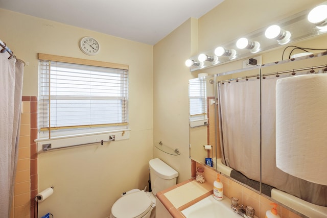 bathroom featuring plenty of natural light, a sink, toilet, and a shower with curtain