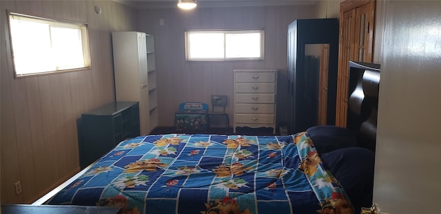 bedroom with multiple windows, ornamental molding, and wood walls
