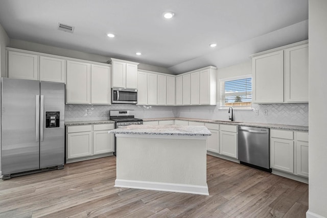 kitchen with white cabinets, a center island, light hardwood / wood-style floors, and appliances with stainless steel finishes