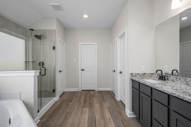 bathroom featuring wood-type flooring, vanity, vaulted ceiling, and walk in shower