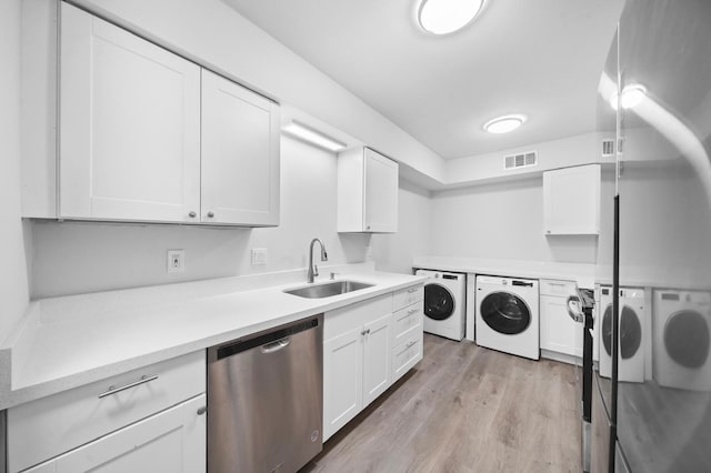 clothes washing area with washer and clothes dryer, light hardwood / wood-style floors, and sink