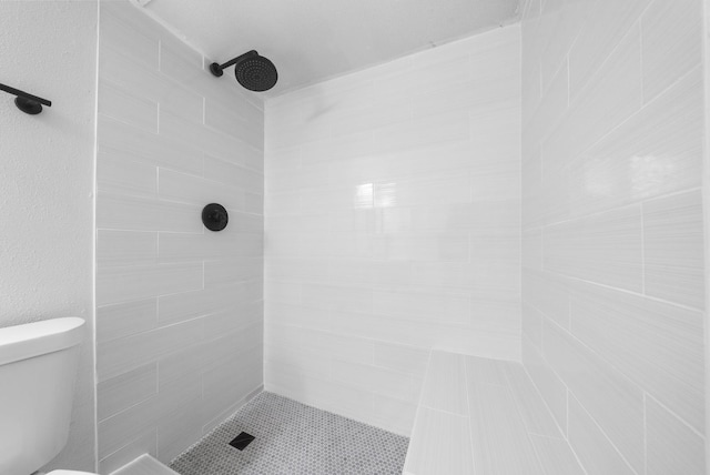 bathroom featuring a tile shower and toilet