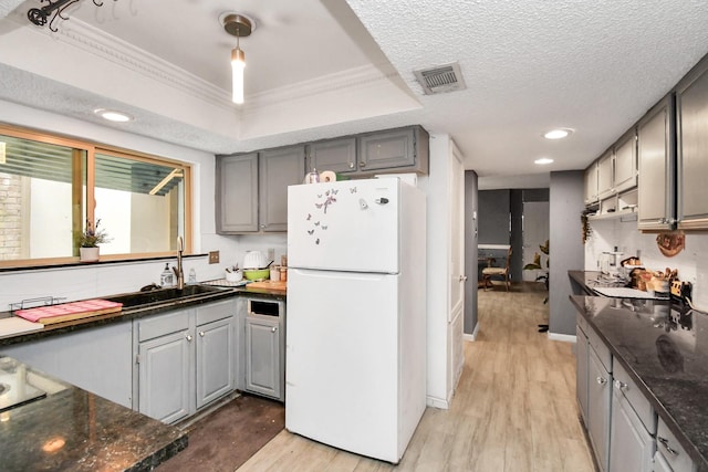 kitchen featuring light wood-type flooring, gray cabinets, white fridge, and a raised ceiling