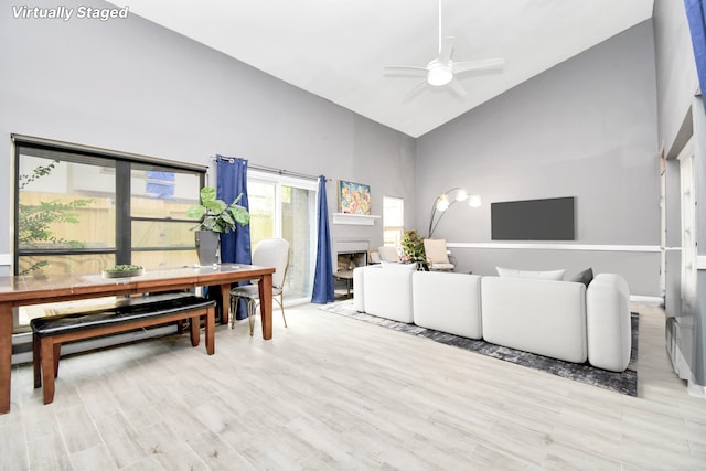 living room featuring ceiling fan, light hardwood / wood-style floors, and high vaulted ceiling