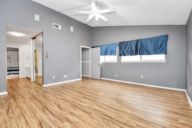 unfurnished bedroom with ceiling fan, light hardwood / wood-style floors, a textured ceiling, and vaulted ceiling