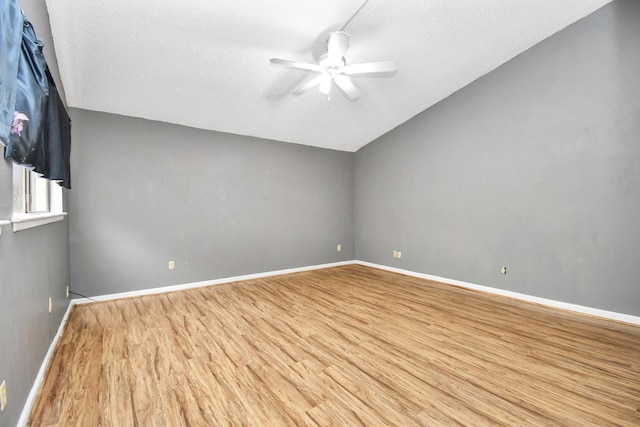 spare room with lofted ceiling, ceiling fan, light wood-type flooring, and a textured ceiling