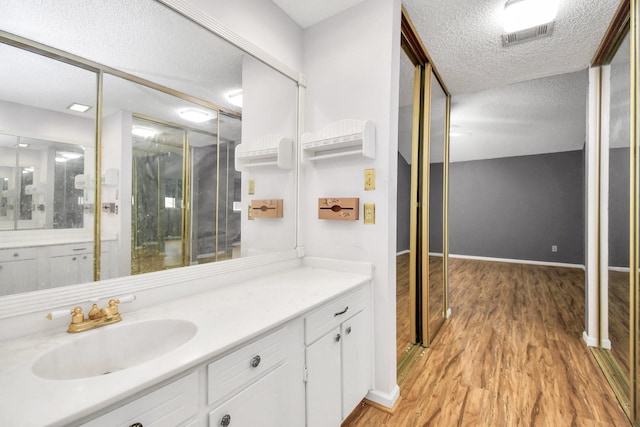 bathroom with hardwood / wood-style flooring, vanity, and a textured ceiling