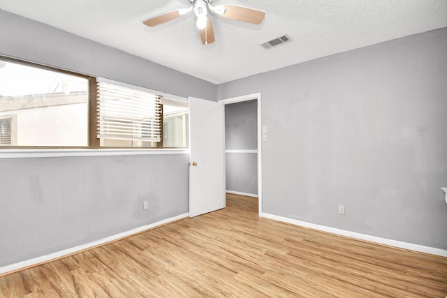 empty room featuring a textured ceiling, light hardwood / wood-style flooring, and ceiling fan