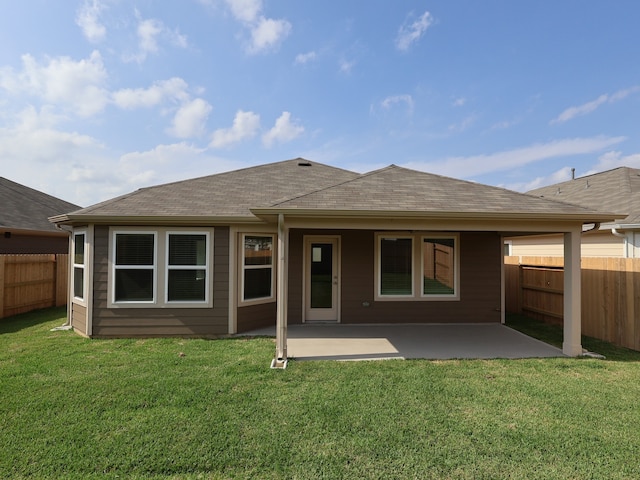 rear view of house featuring a lawn, a patio area, roof with shingles, and a fenced backyard